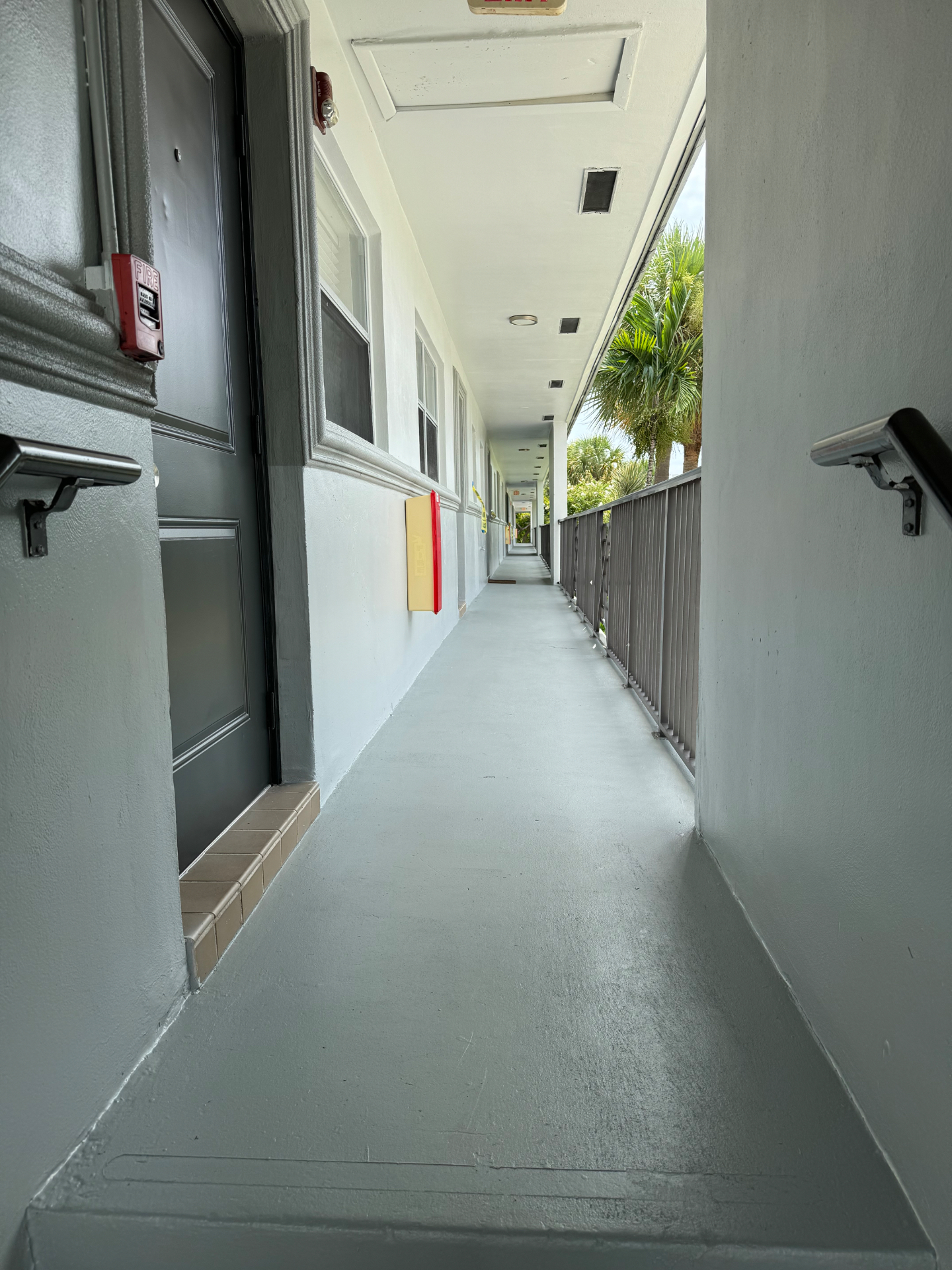 Repainted breezeway with refreshed trim and railings at a garden-style multifamily community in Pompano Beach